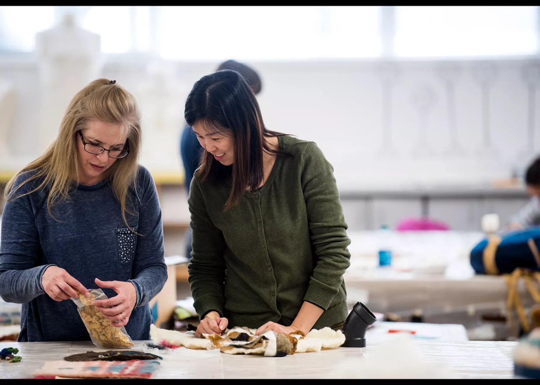 Professor shows student different materials in Fiber Arts class