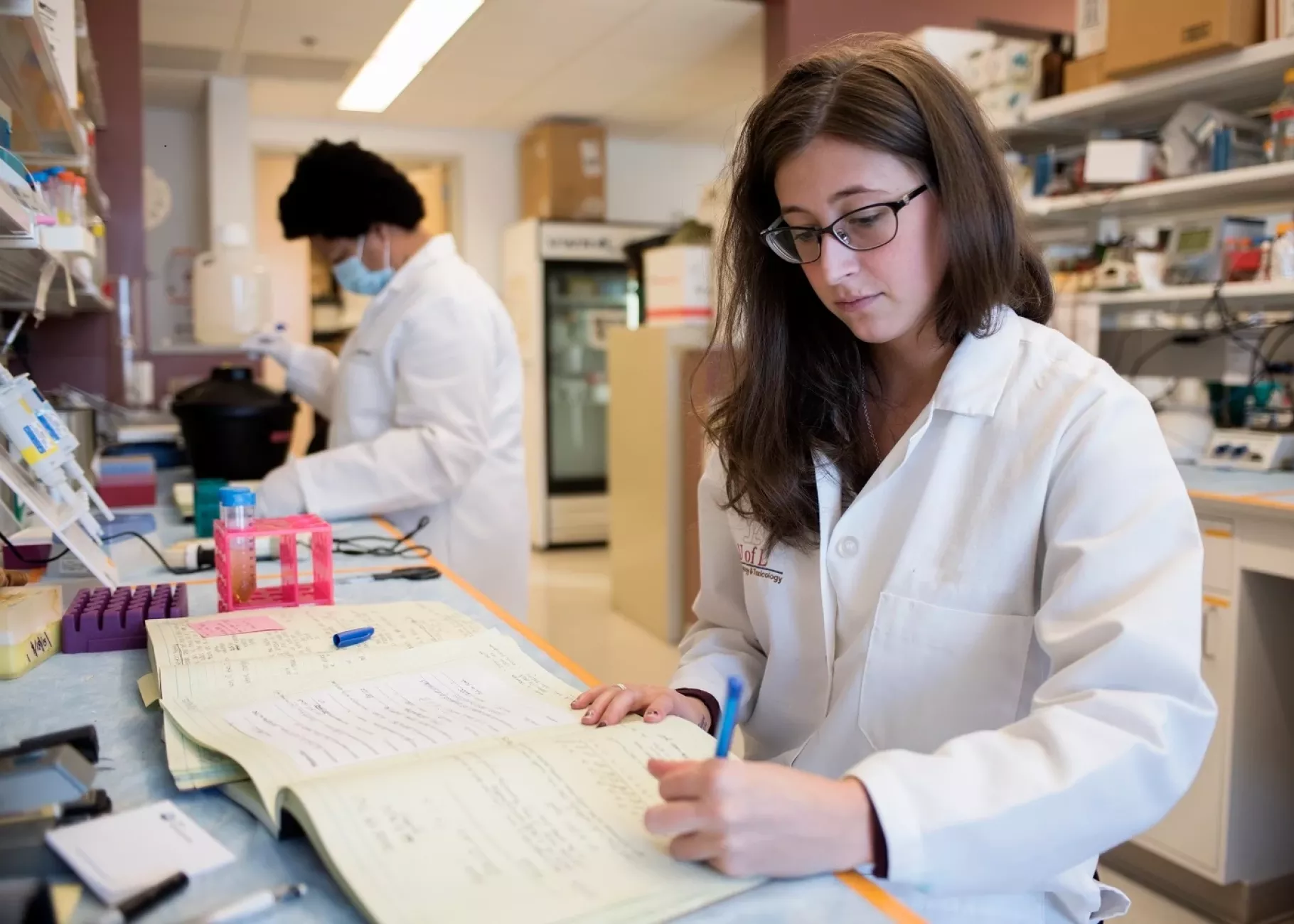 Woman writing in a lab setting.