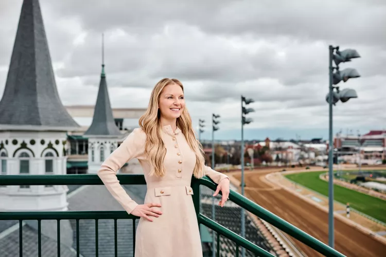 A smiling young woman standing in front of the twin spires at Churchill Downs