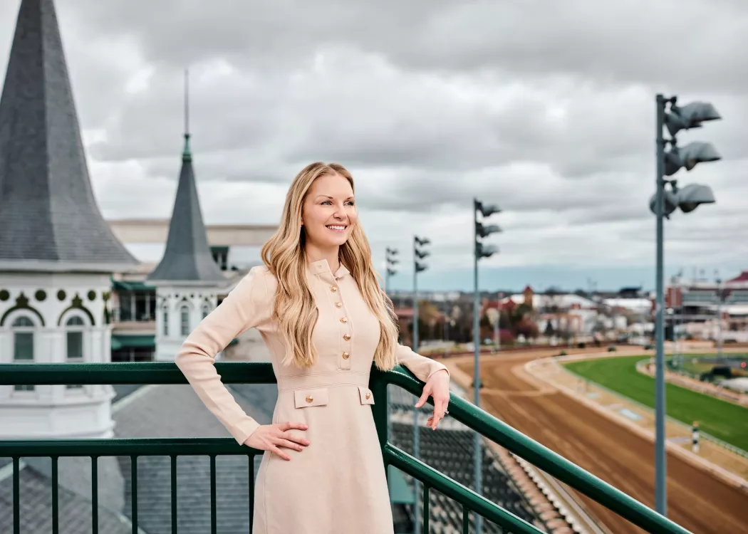 A smiling young woman standing in front of the twin spires at Churchill Downs