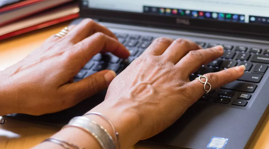 Employee typing on laptop in a UofL office