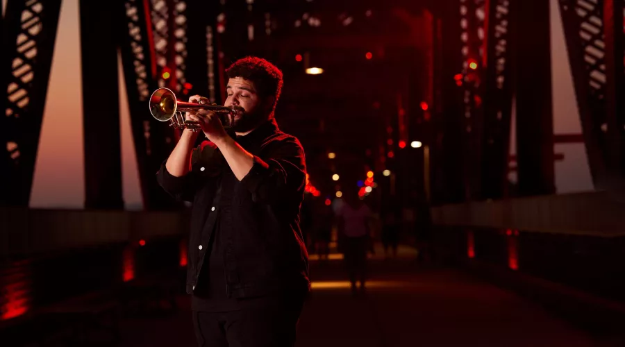 Connor May can be seen playing his trumpet on Big Four Bridge during the sunset.
