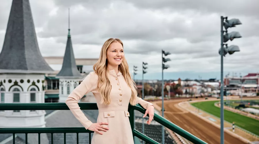 A smiling young woman standing in front of the twin spires at Churchill Downs