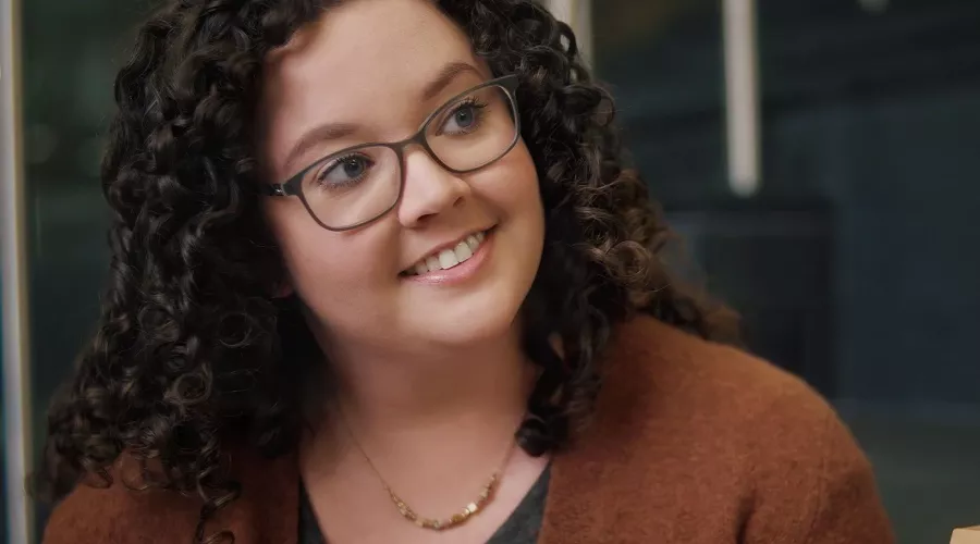 A smiling woman with glasses in conversation.
