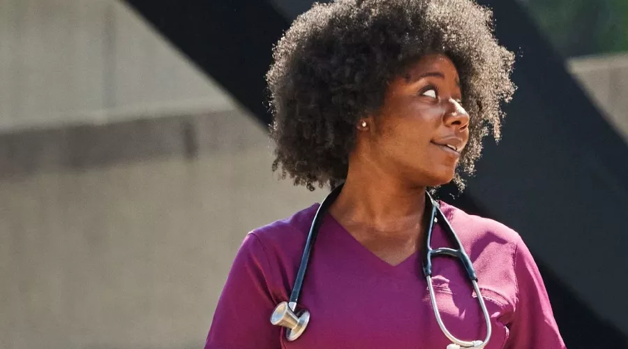 A woman in purple medical scrubs having a conversation outside.